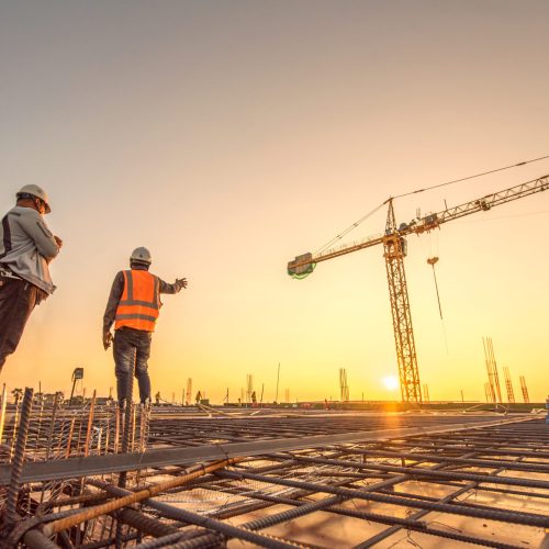silhouette group of worker and civil engineer  in safety uniform install reinforced steel column in construction site during sunset time industrial concept